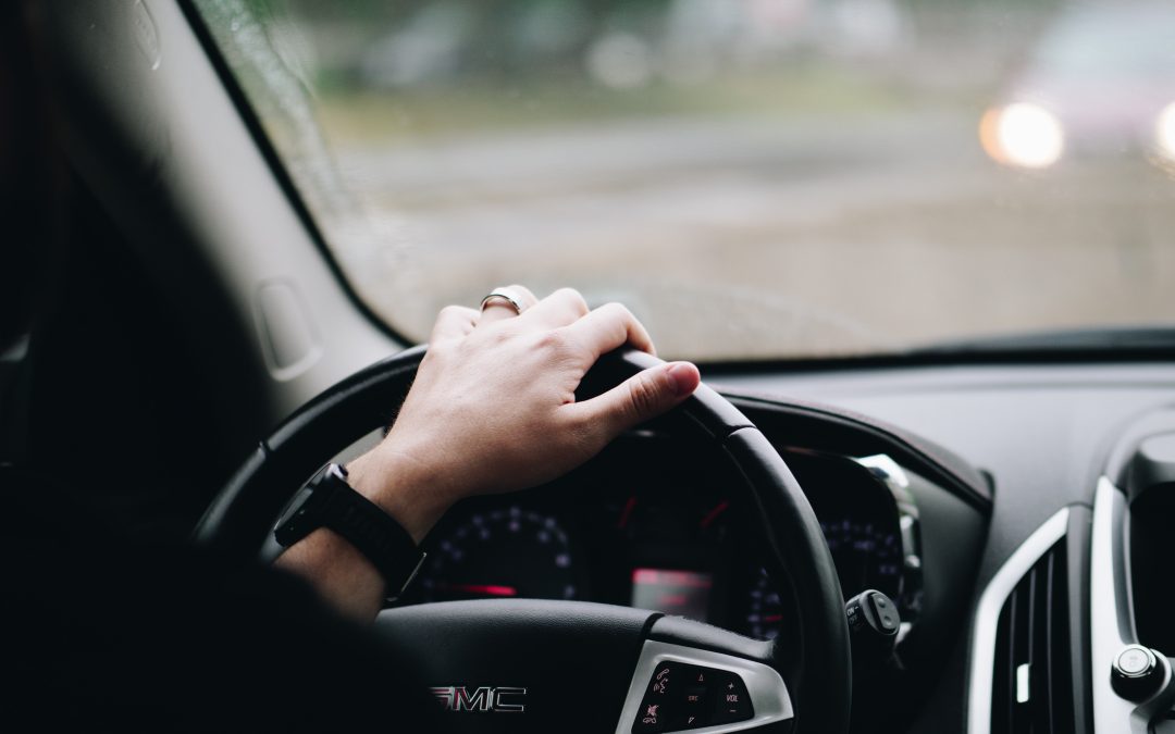 Hand gripping the steering wheel of a vehicle, demonstrating safe driving practices essential for passing the New York road test.
