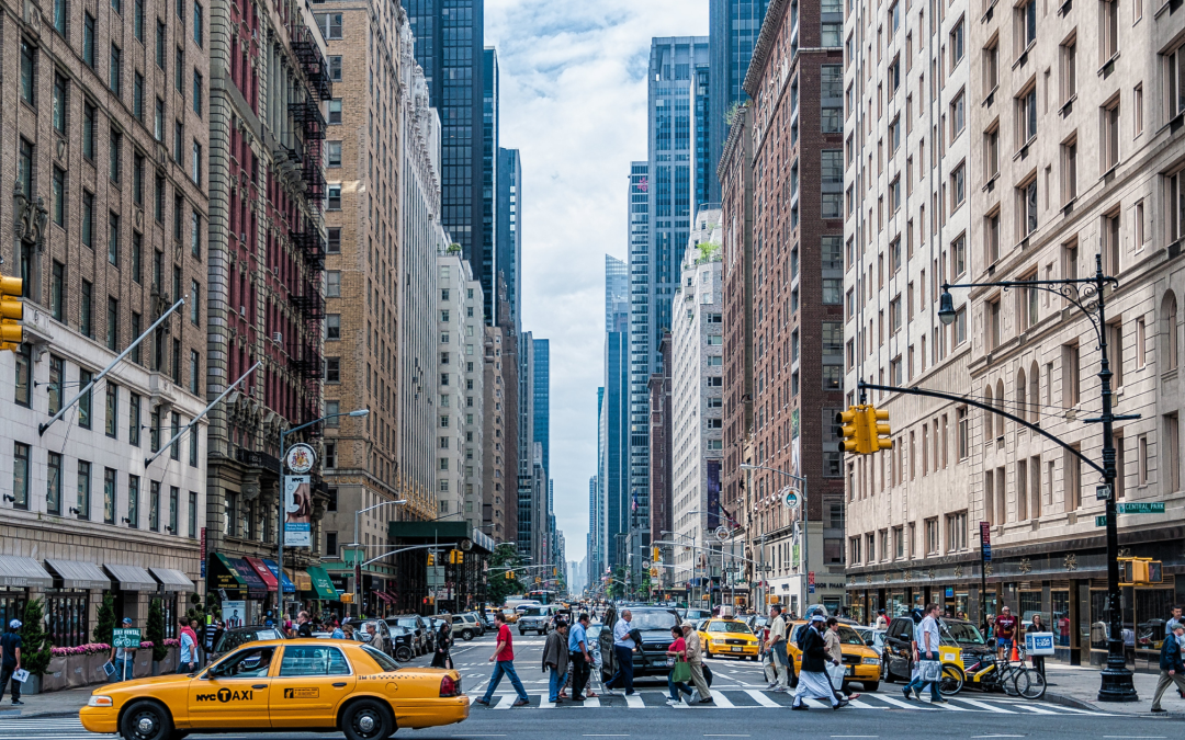 Busy New York City street scene with yellow taxis, pedestrians crossing, and tall buildings, illustrating urban driving conditions relevant to road test preparation.