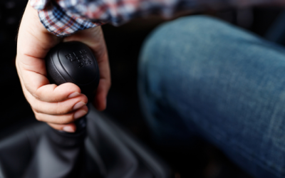 Hand gripping manual transmission gear shift, illustrating driving technique for road tests.