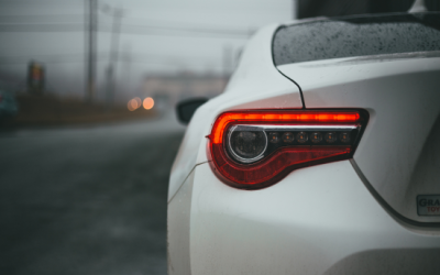 Car tail light illuminated on a rainy road, emphasizing vehicle visibility and safety during driving tests.