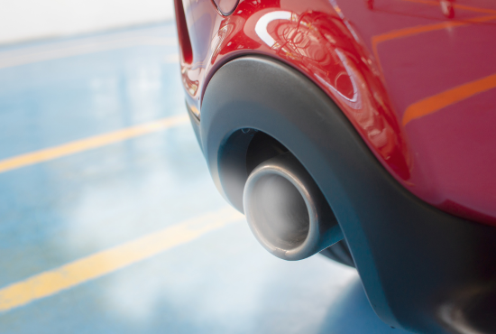 Close-up of a vehicle's exhaust pipe emitting exhaust smoke, highlighting vehicle readiness for road tests and inspection.