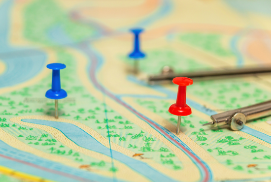 Map with red and blue push pins marking test routes, compass tools, and winding roads, illustrating navigation challenges for road test preparation.