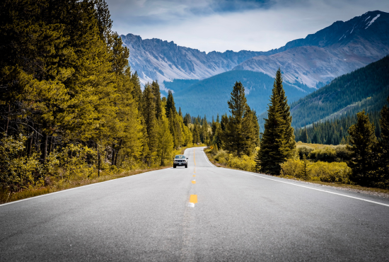 Scenic road surrounded by trees and mountains, illustrating safe driving conditions for road tests and vehicle maintenance.