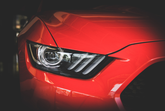 Close-up of a red vehicle's headlight, showcasing modern design and clarity, relevant to vehicle safety checks before a road test.