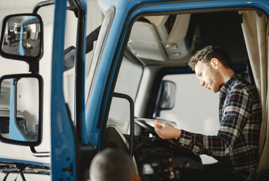 Man examining vehicle controls in a blue truck cabin, emphasizing vehicle operation and safety checks relevant to roadworthiness testing.