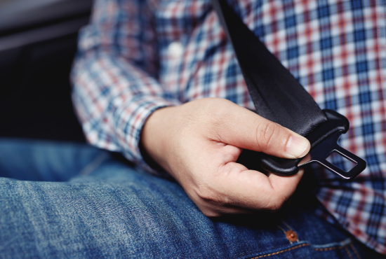 Person fastening a seat belt in a vehicle, emphasizing safety and functionality of seat belts.