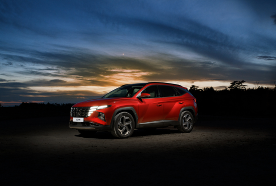 Red SUV parked in a dimly lit area against a dramatic sunset, showcasing its design and features relevant to safe driving practices during road tests.