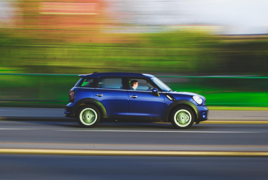 Blue compact car in motion on a road, illustrating speed and driving dynamics relevant to road test preparation.