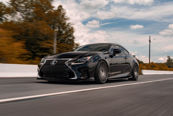 Black Lexus coupe driving on a road, symbolizing confidence and performance in road test preparation.
