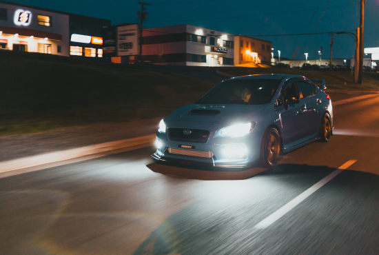 Car driving on a road at night with illuminated headlights, representing vehicle readiness for road tests and driving safety.