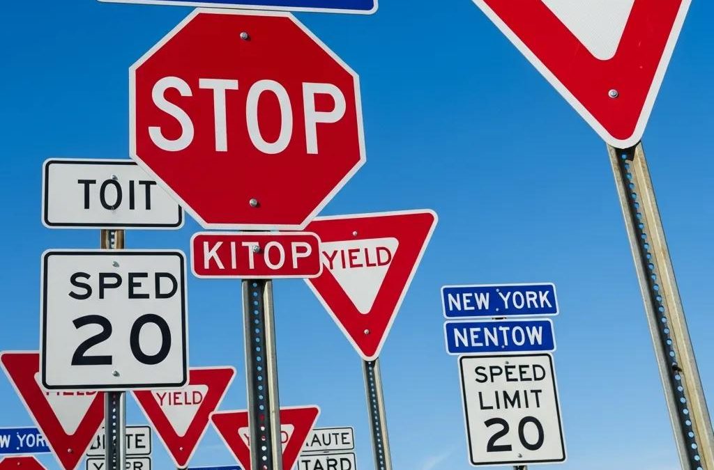 New York road signs including stop, yield, and speed limit signs against a blue sky, emphasizing road safety for new drivers
